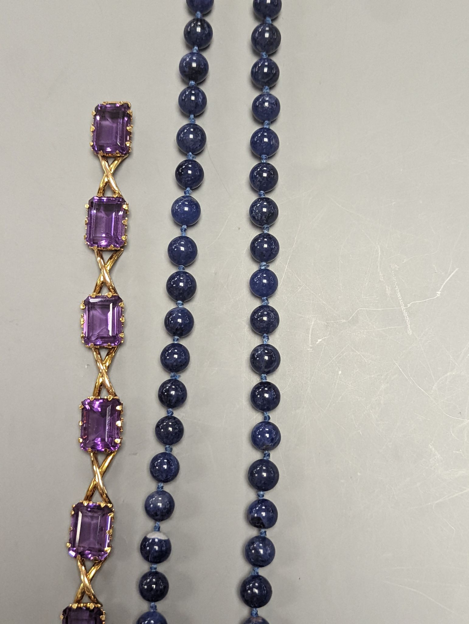 A yellow metal and six stone emerald cut amethyst set part bracelet(a.f.), 17.1cm and a modern single strand lapis lazuli bead necklace with 14k yellow metal clasp.